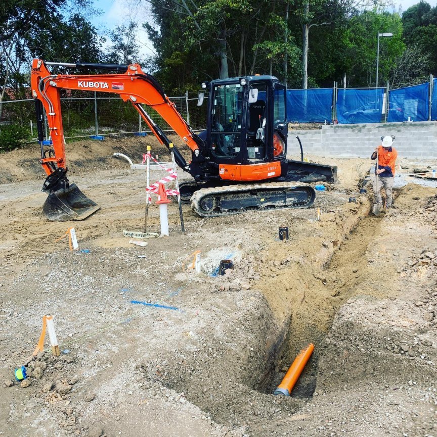 Excavator trenching for underground electrical conduit